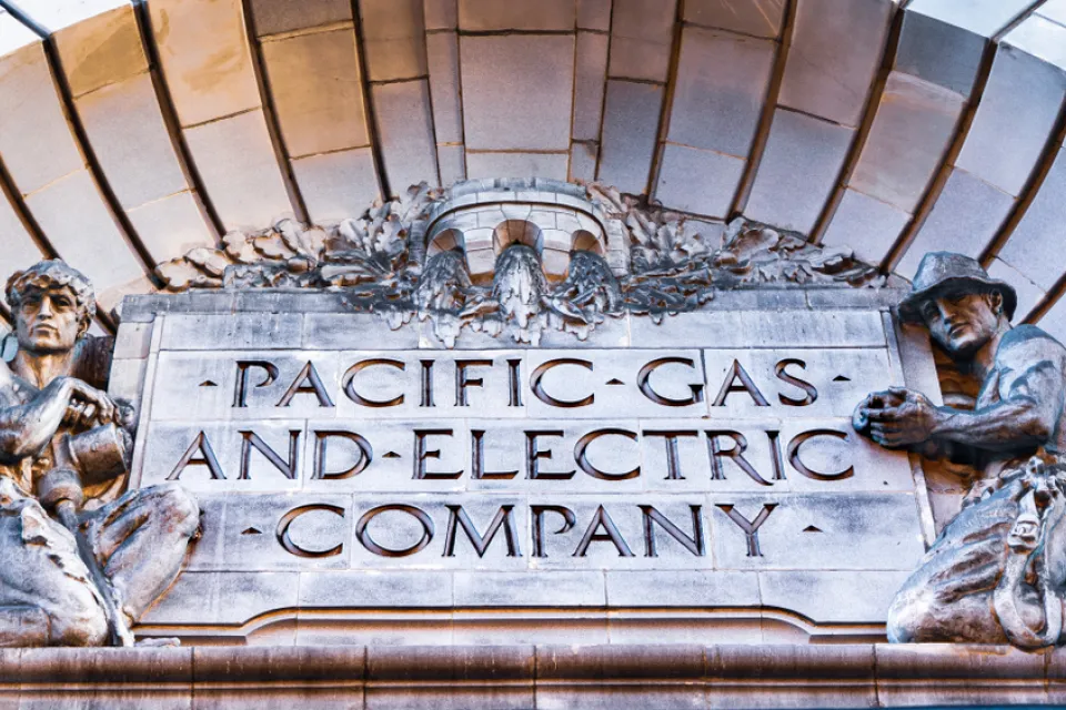 Close-up of Pacific Gas & Electric Company title carved into building facade, flanked by two statues of utility workers